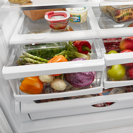 Partially opened drawers loaded with fruit and vegetables.