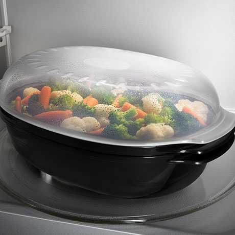 Covered dish of vegetables being steamed in the microwave.