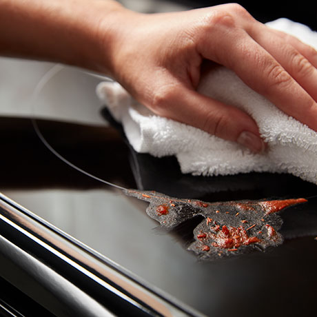 Hand wiping up a spill on the cooktop
