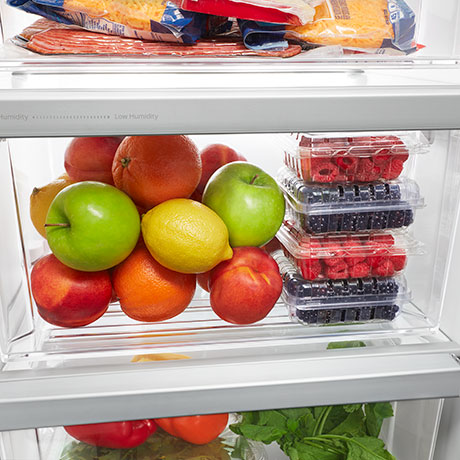 Closed crisper drawer that is filled with fruit and fully lit.